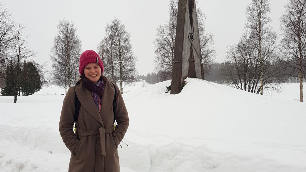 Woman outdoor in a snowy park. A statue in the shape of a clothespin. Photo.