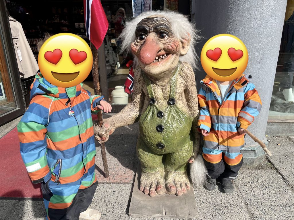 Two kids and a troll statue. Photo. 