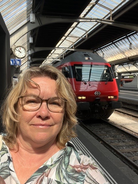 Person at train station in front of a train. Photo.
